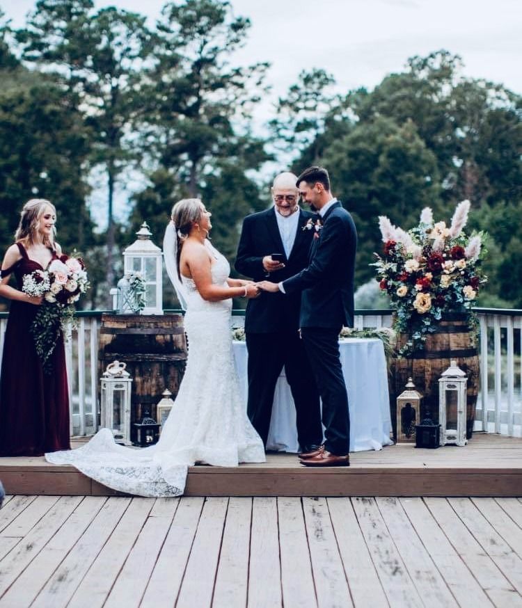 Outdoor wedding ceremony with bride and groom exchanging rings on a wooden deck