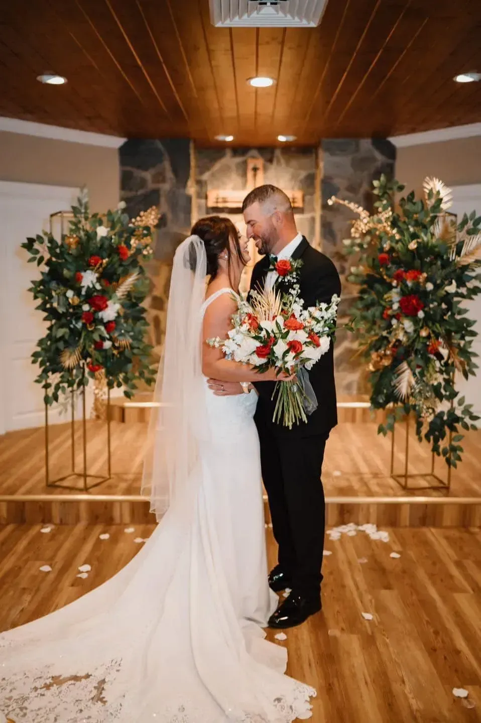 Bride and groom kissing at a decorated wedding altar with floral arrangements and wooden ceiling