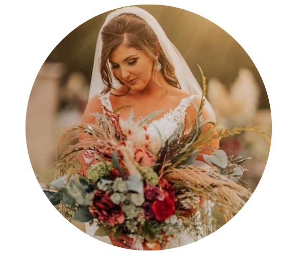 Bride holding a rustic bouquet, looking down in a soft outdoor portrait