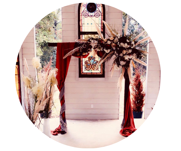 Floral wedding arch with red drapes and black-and-white arrangements in a bright indoor venue