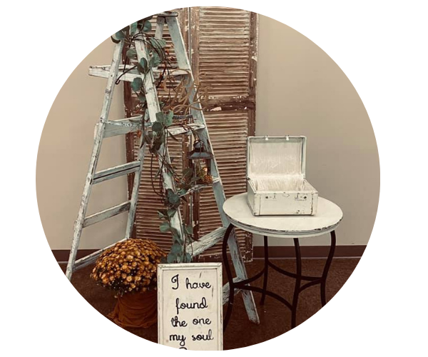 Ladder and stacked wood beside a small table with an open white box and a handwritten sign.