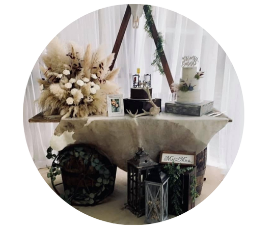 Decorated table with dried flowers, candles, lanterns, and a fur throw in a soft, elegant indoor display