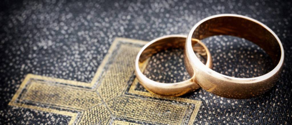 A pair of wedding rings sitting on top of a bible.
