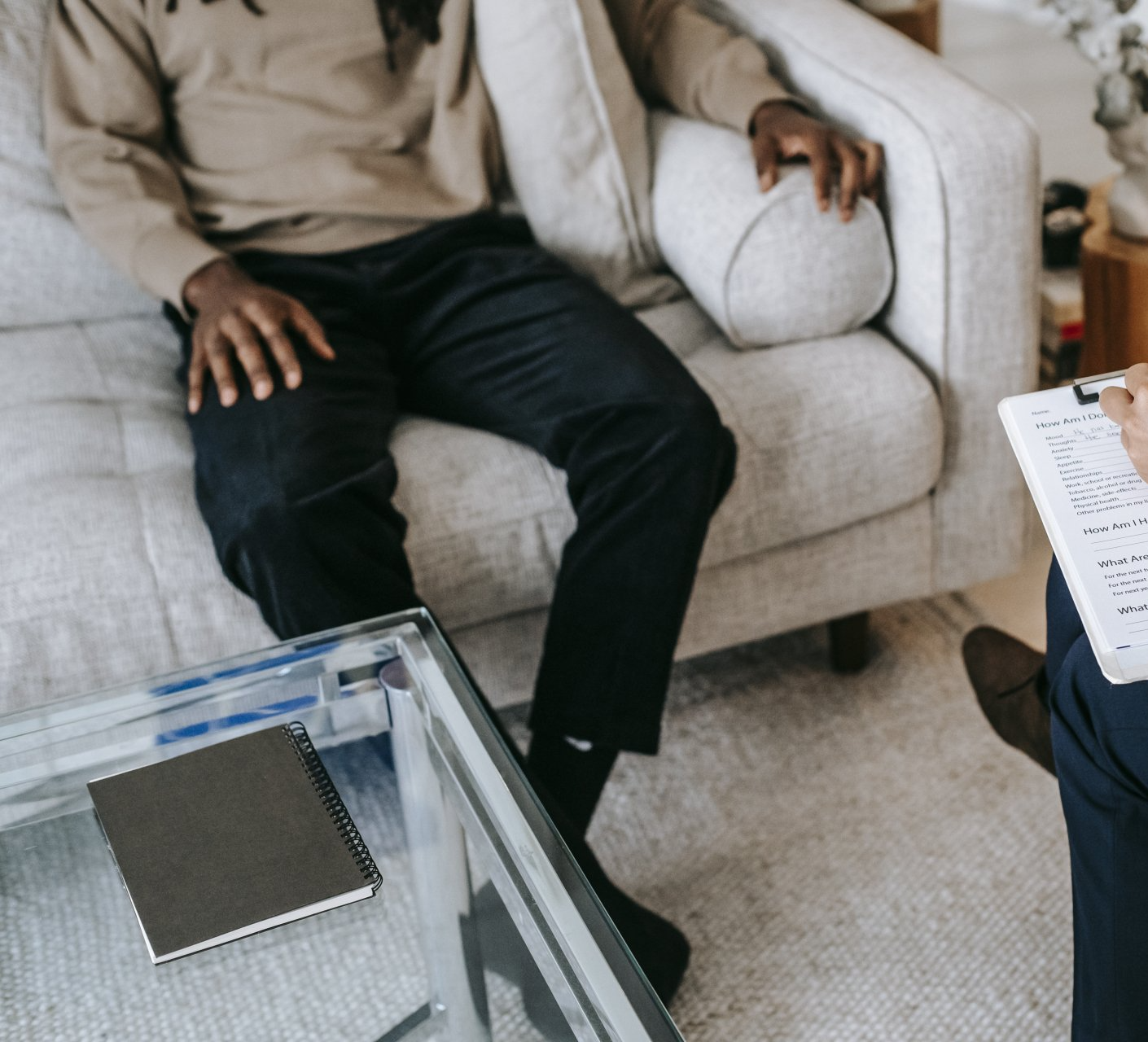 A man is sitting on a couch talking to a counselor. Receiving catholic trauma counseling in Grapevine Texas.