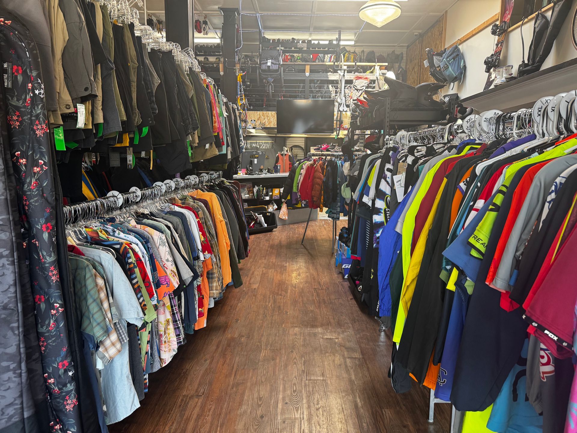 Clothing boutique aisle lined with colorful jackets, shirts, and dresses on both sides
