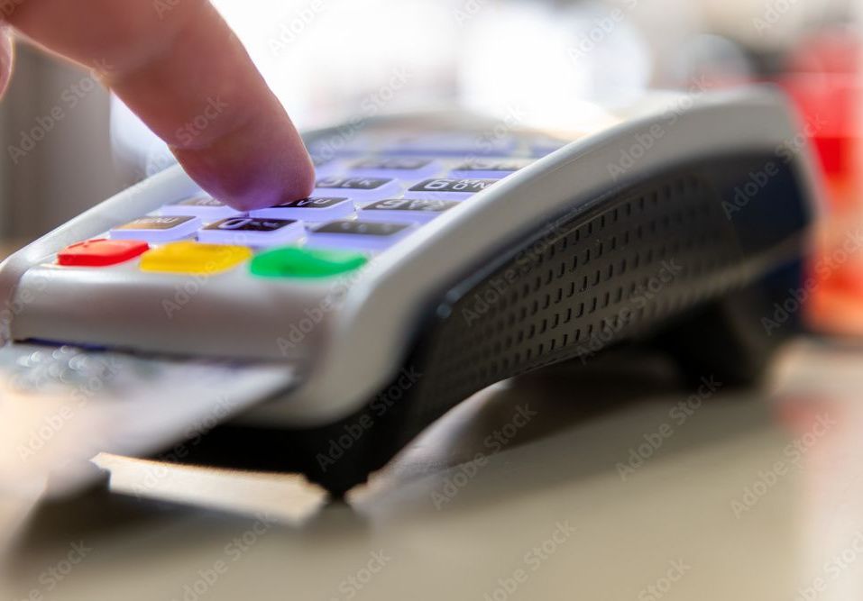 Finger presses buttons on a credit card reader, card inserted.