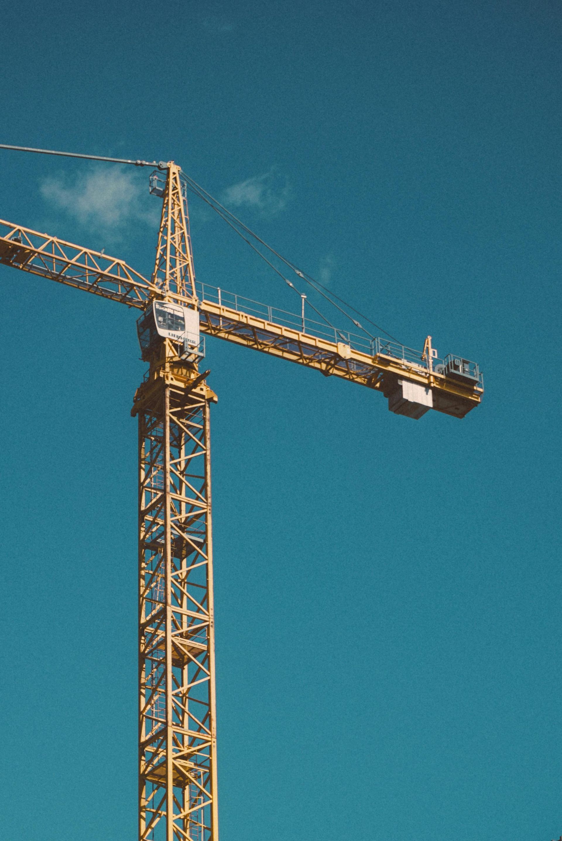 Yellow construction crane against a bright blue sky.