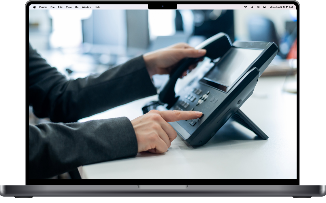 Person using a desk phone, dialing a number in an office setting.