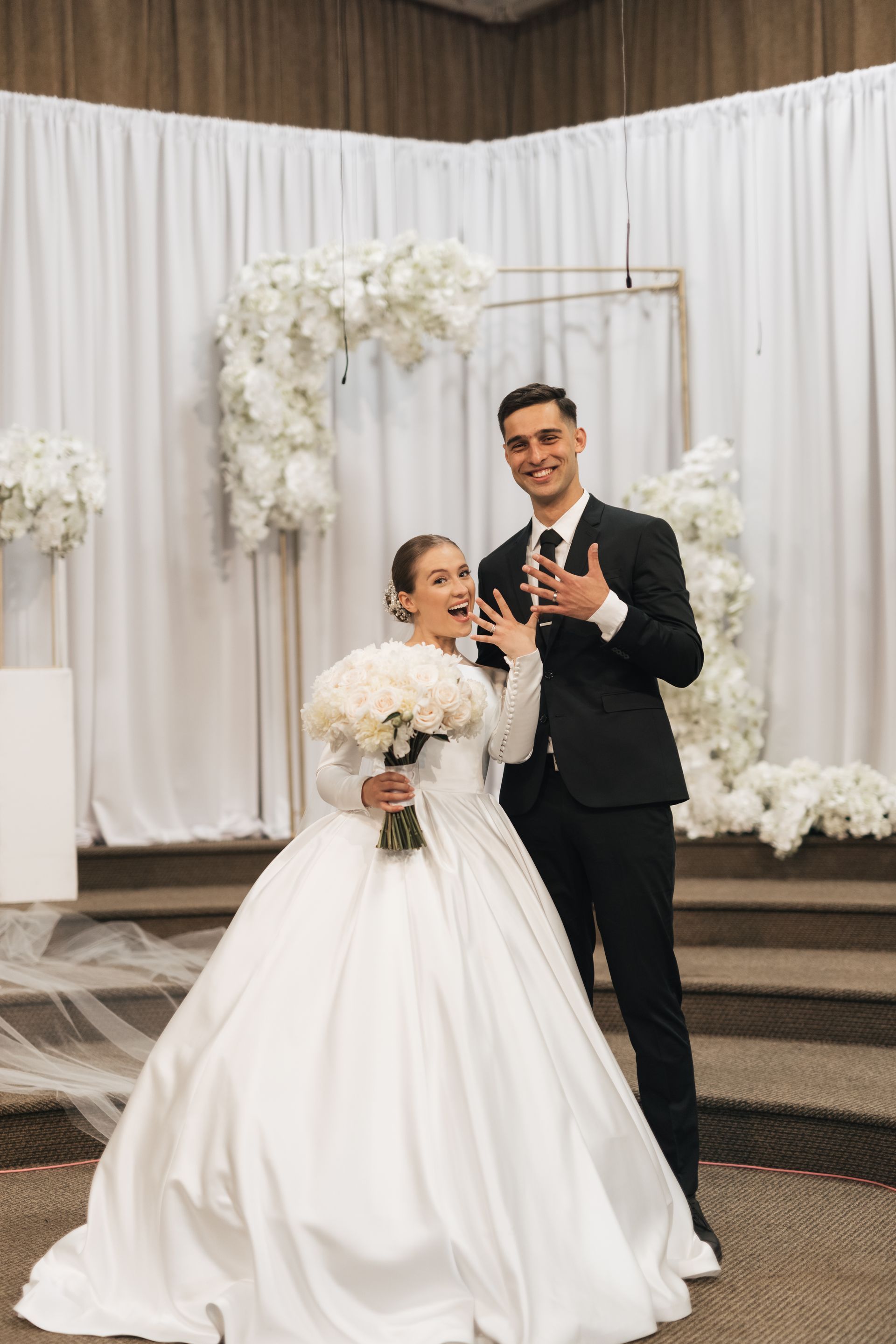 A bride and groom are posing for a picture at their wedding.