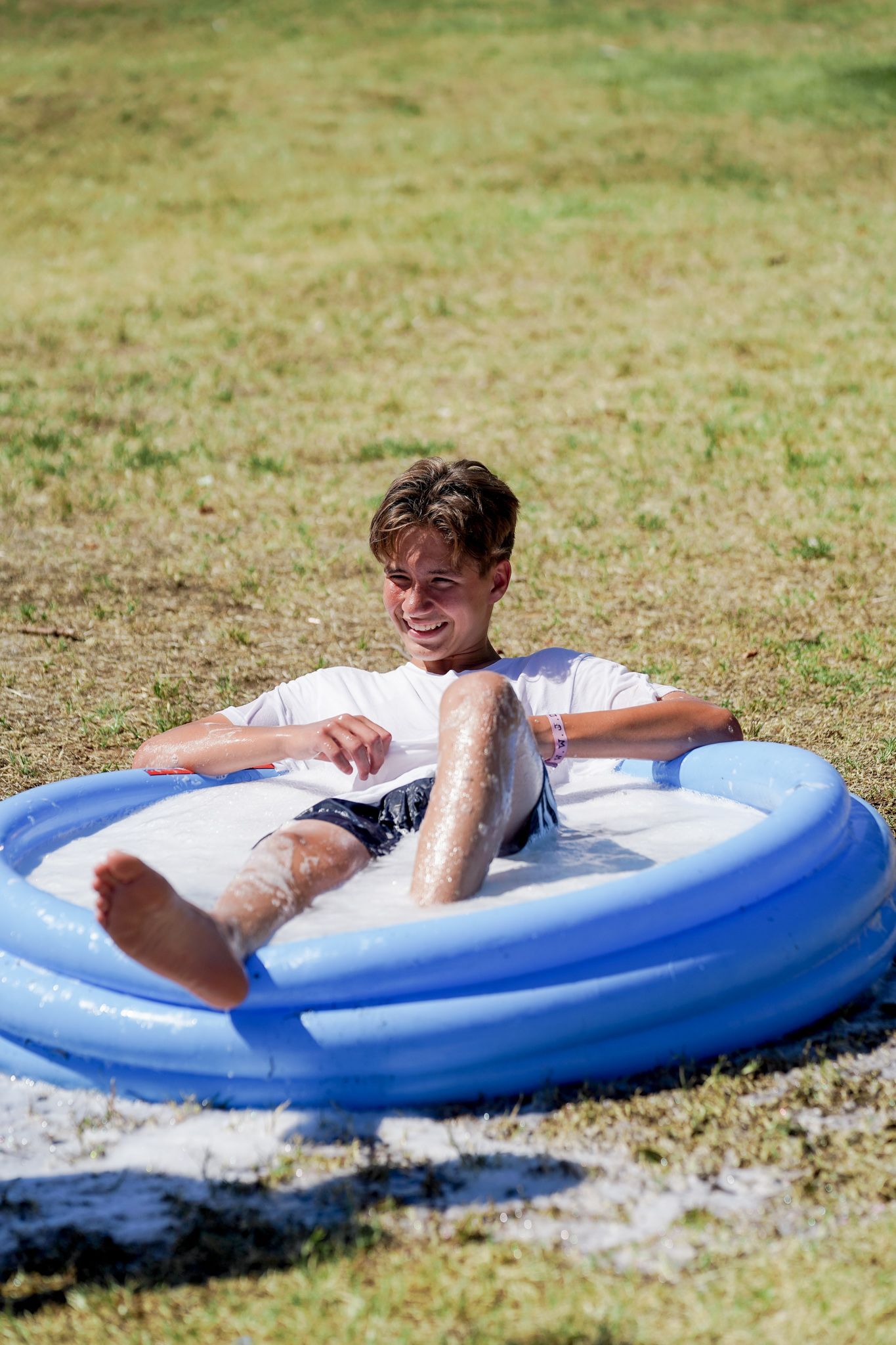 A young boy is sitting in an inflatable pool.