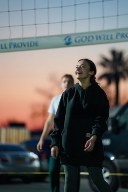 A woman stands in front of a volleyball net that says god will provide
