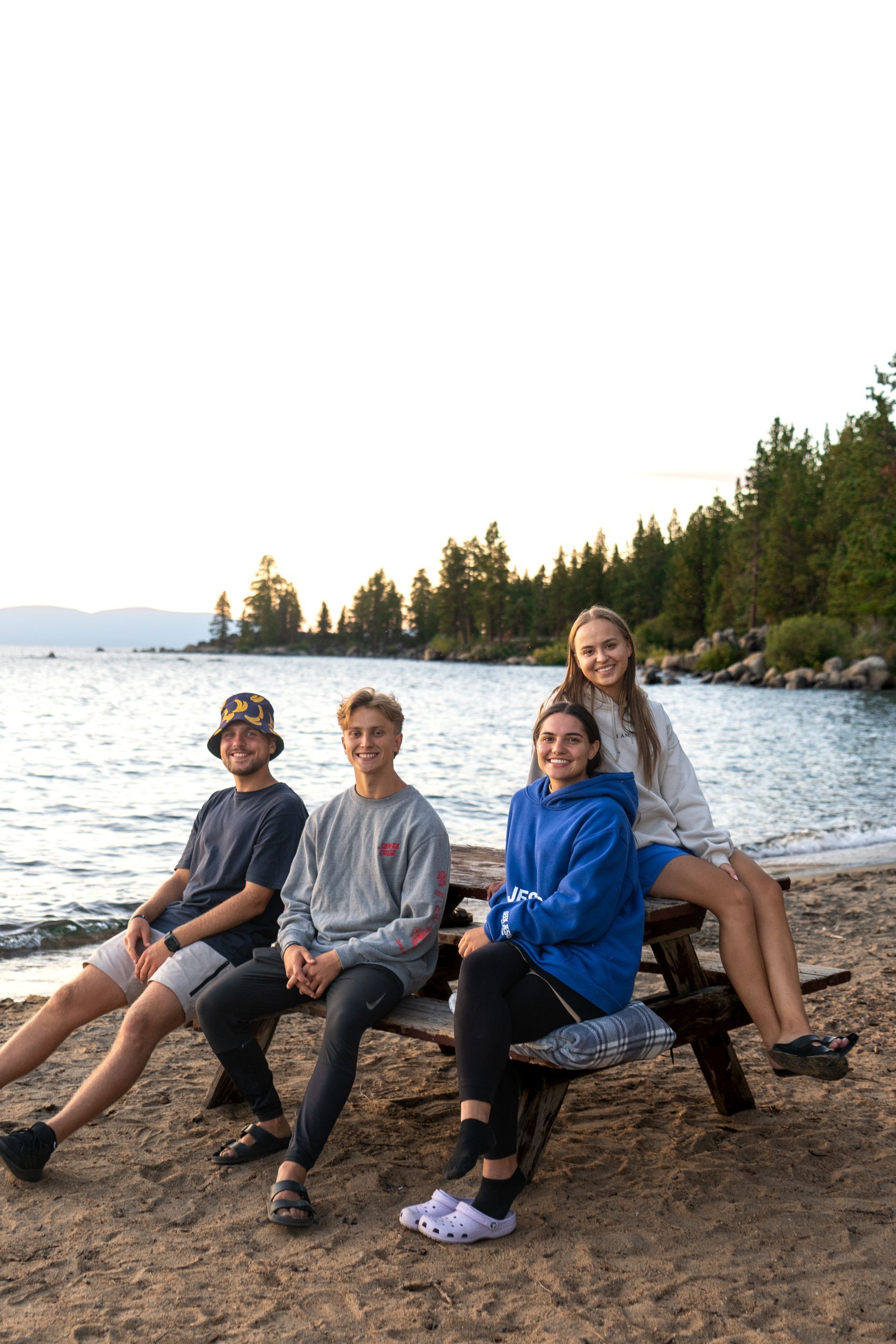 A group of people are sitting on a picnic table on the beach.