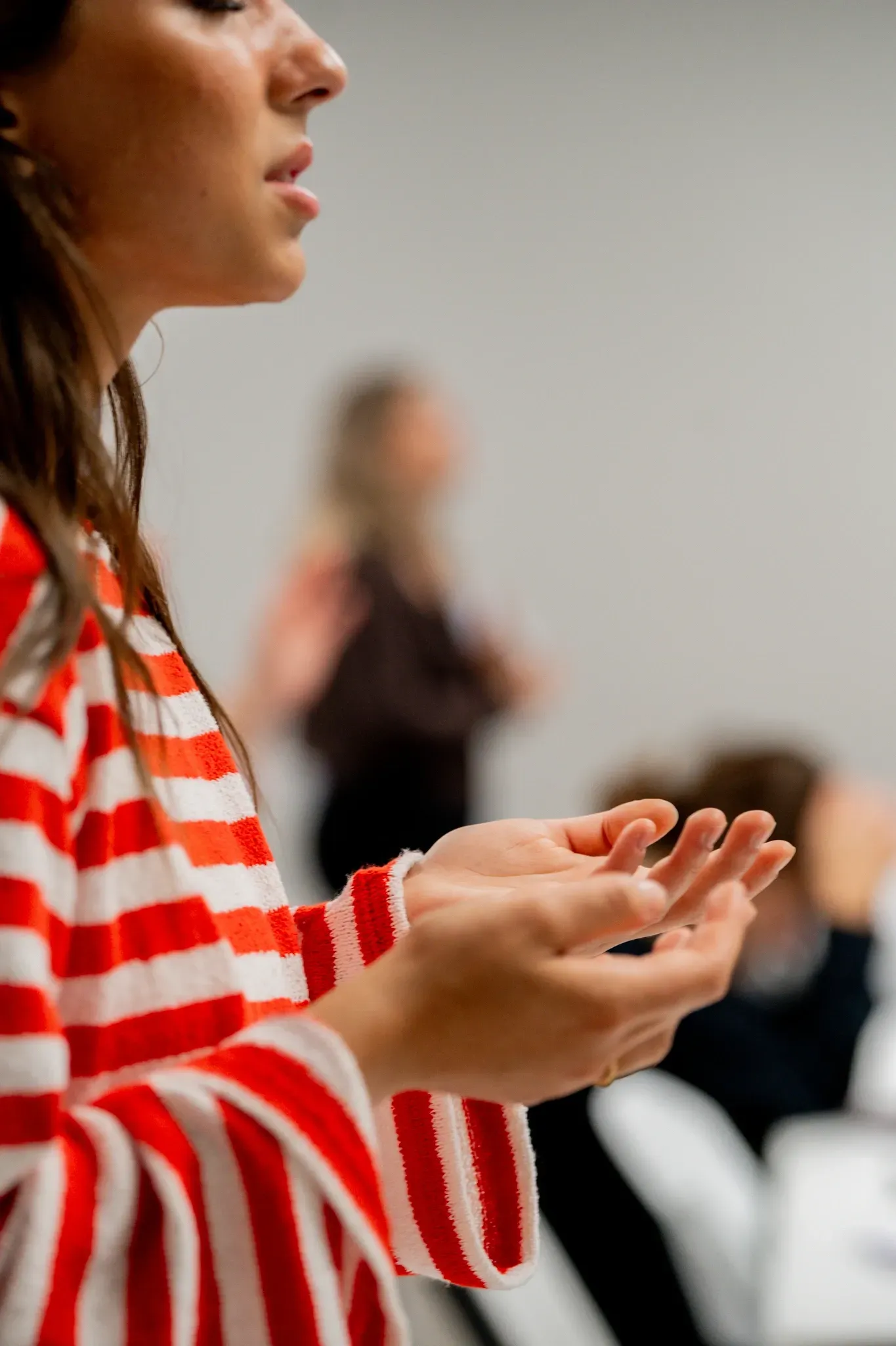 A woman in a red and white striped shirt is clapping her hands.