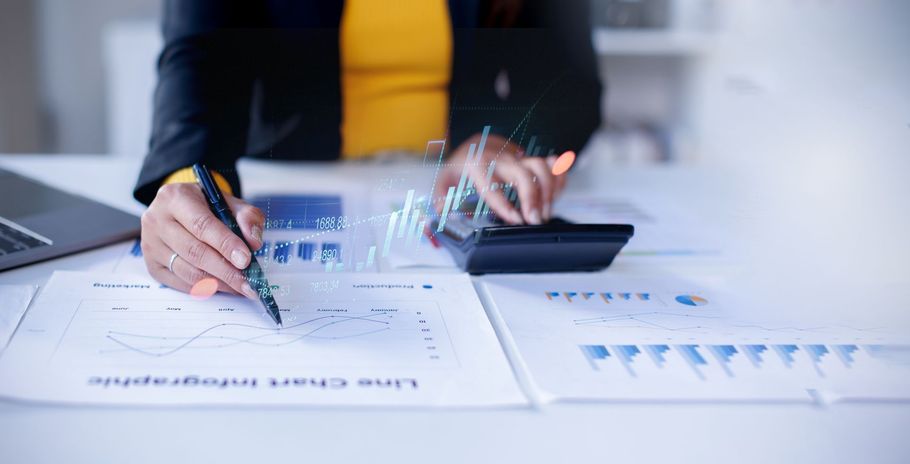 Hands reviewing printed charts with a calculator on a desk in an office