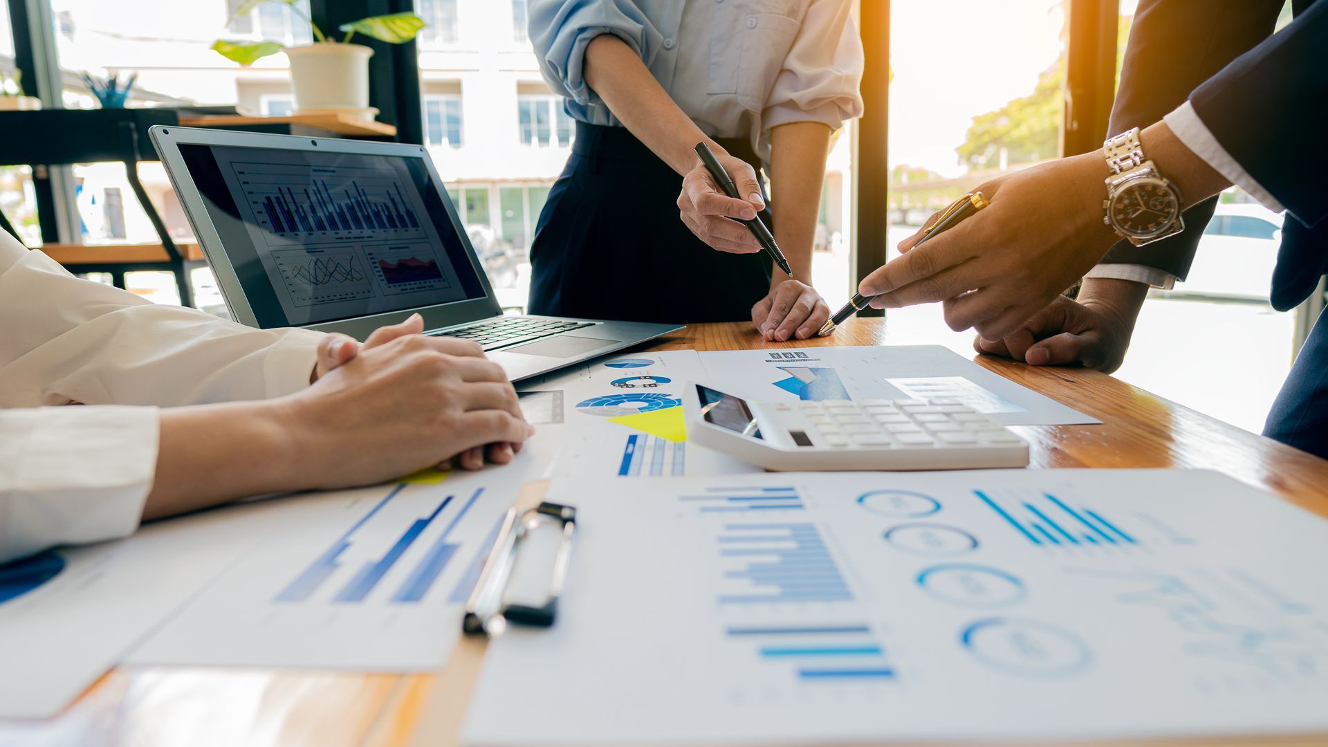 People reviewing charts and graphs around a table in a bright office meeting