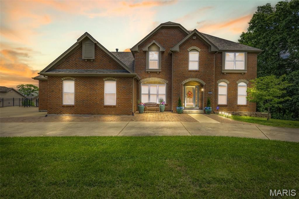 Large brick house with a two-car garage at sunset, front lawn in the foreground