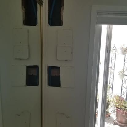 Closed white double doors with small square windows, beside an open doorway to a bright patio.