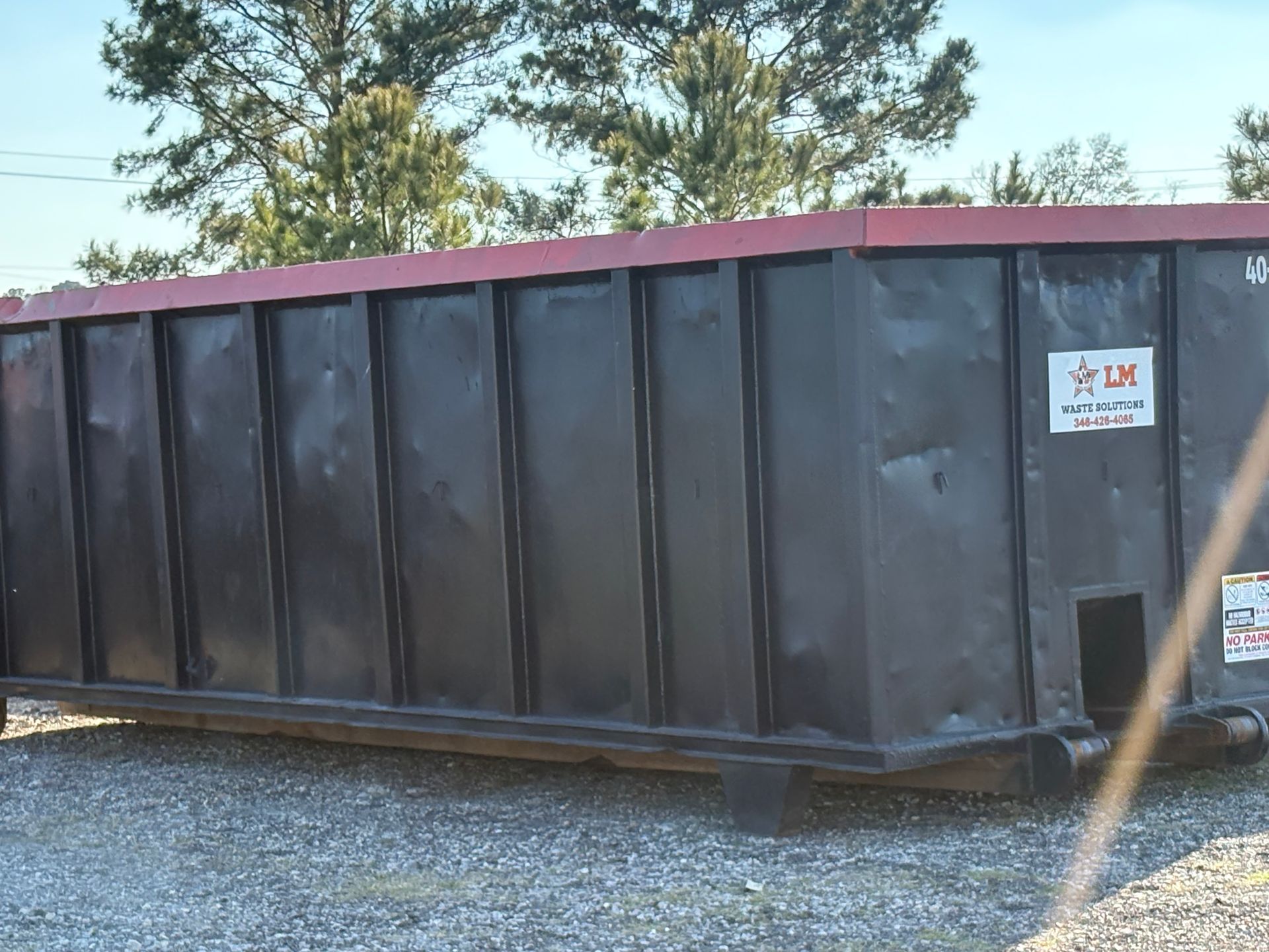 Green dumpster overflowing with cardboard boxes and trash on a city street
