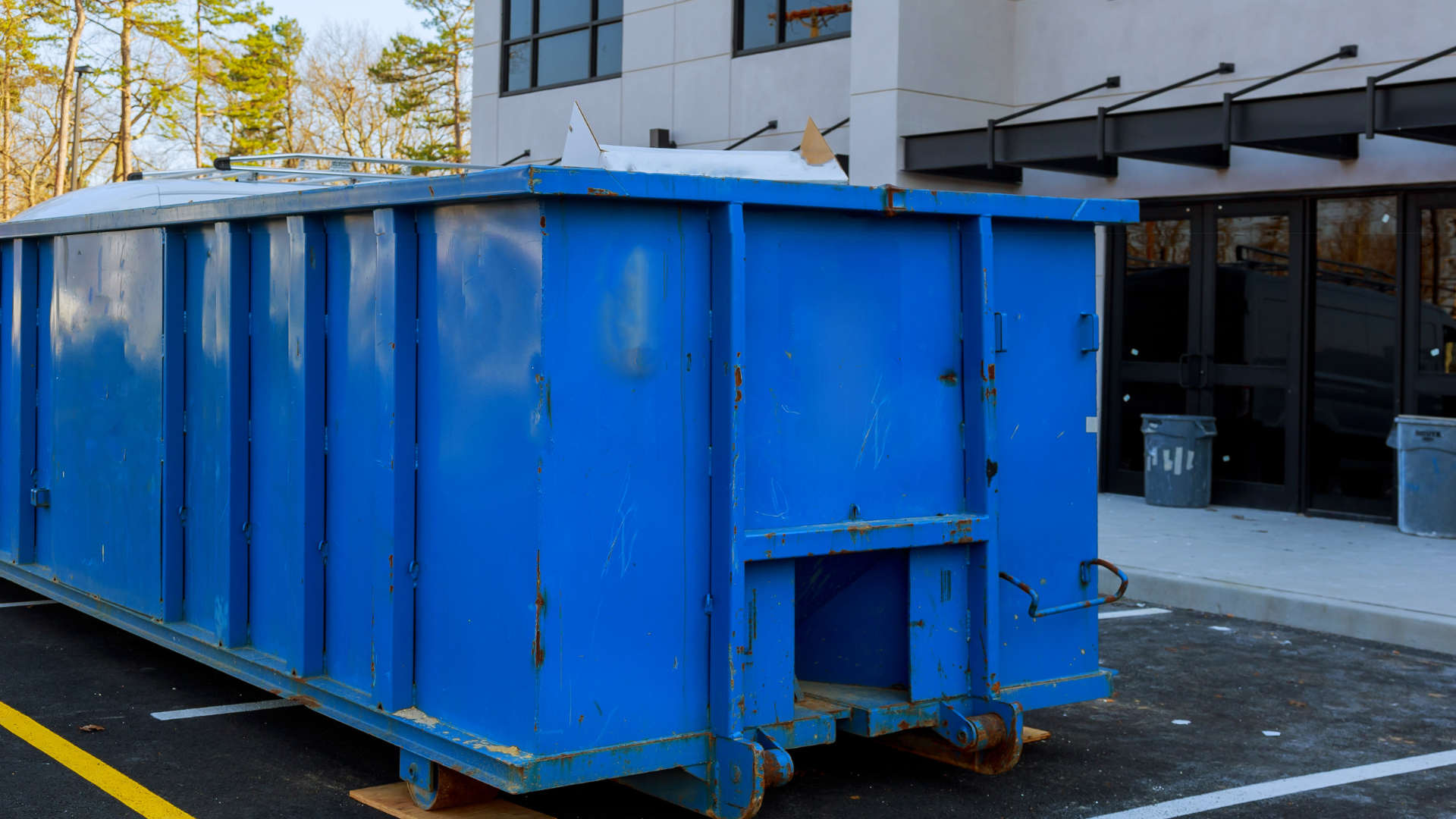 Green dumpster overflowing with cardboard boxes and trash on a city street