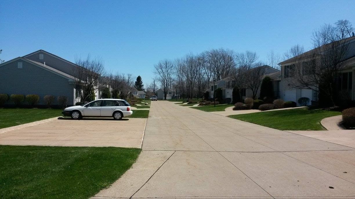 Residential street with houses and parked car on a sunny day.