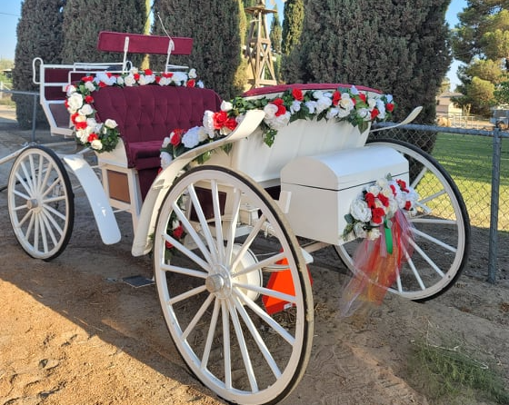 A white horse drawn carriage decorated with red and white flowers