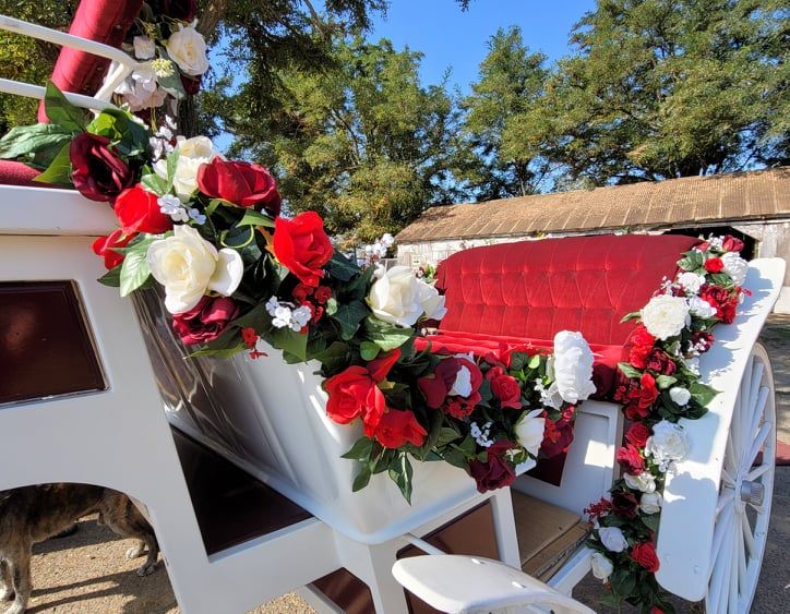 A horse drawn carriage decorated with red and white flowers