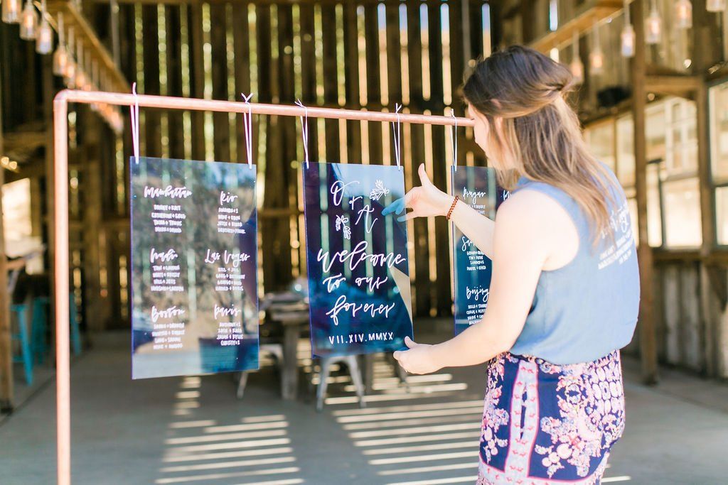 A woman is standing in front of a table plan in a barn.