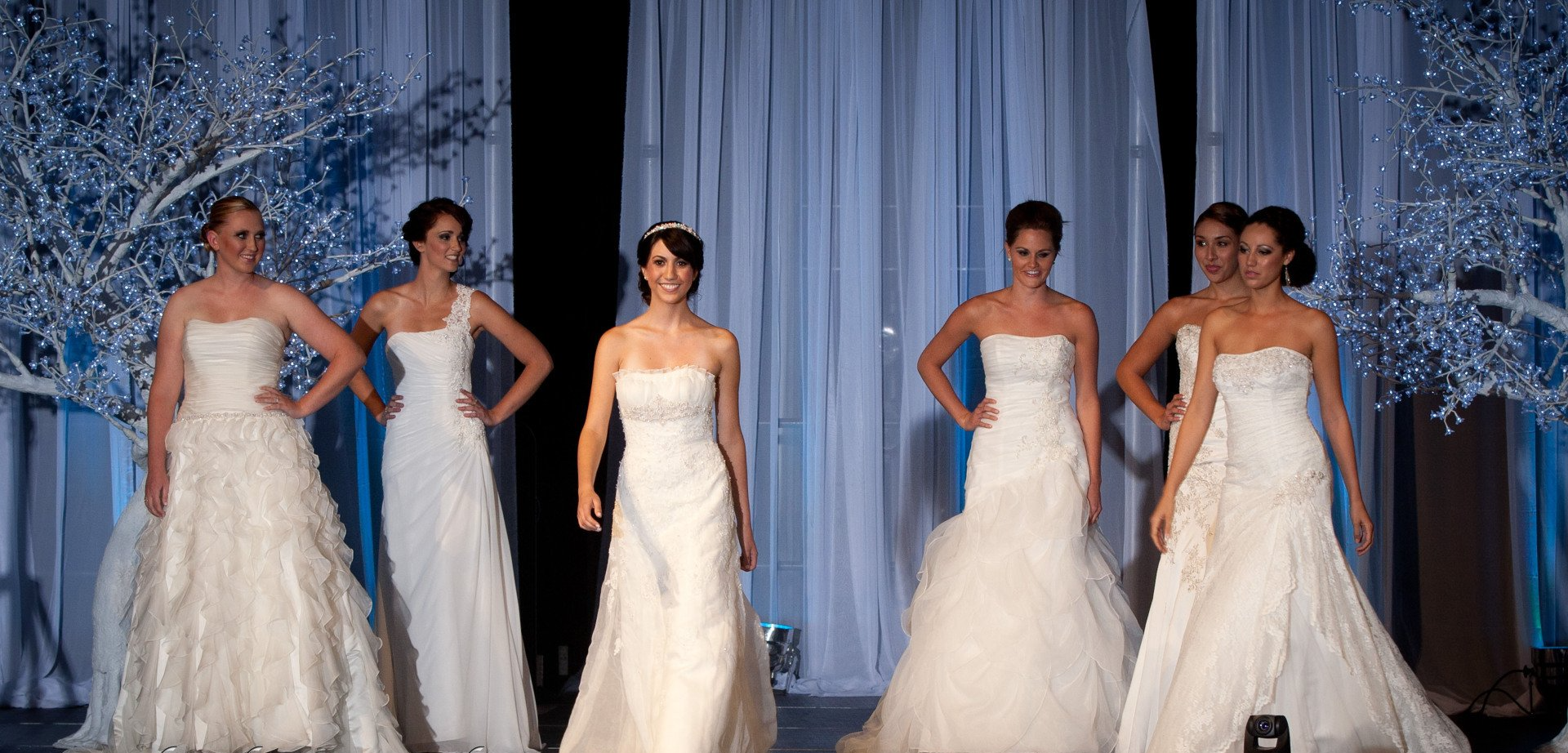 A group of women in wedding dresses are walking down a runway.