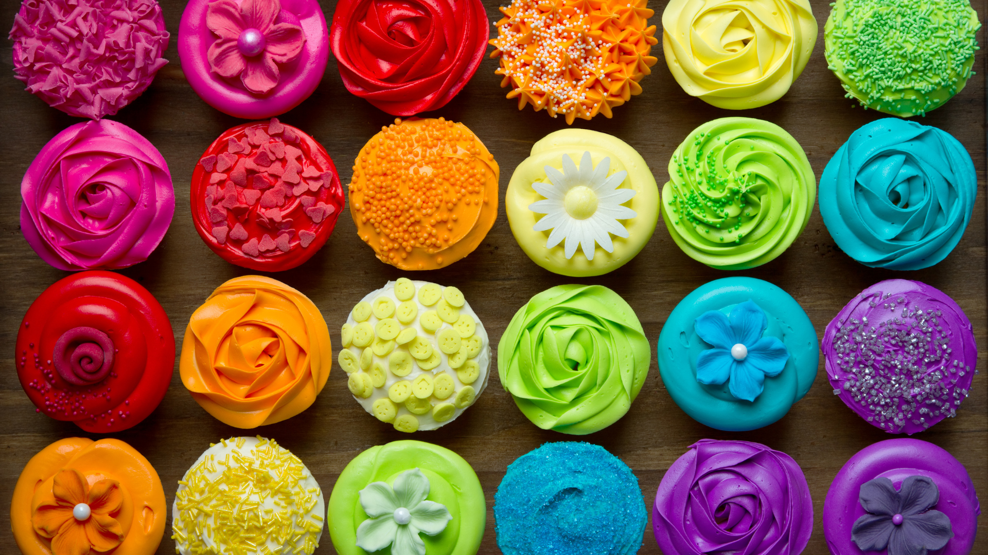 A bunch of colorful cupcakes are sitting on a table.