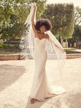 A woman in a wedding dress and veil is standing in a park.