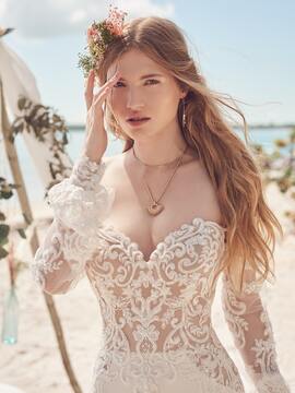 A woman in a wedding dress is standing on a beach.