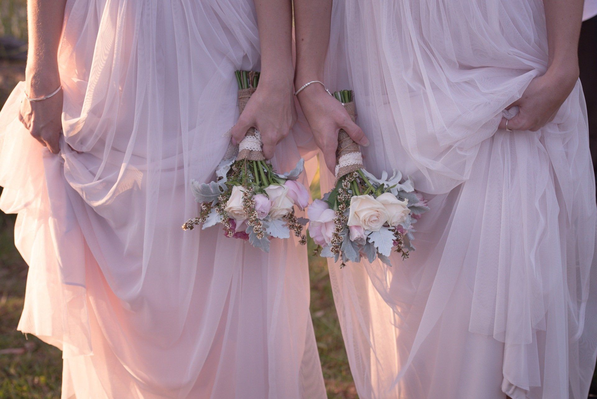 A group of bridesmaids in pink dresses holding bouquets of flowers.