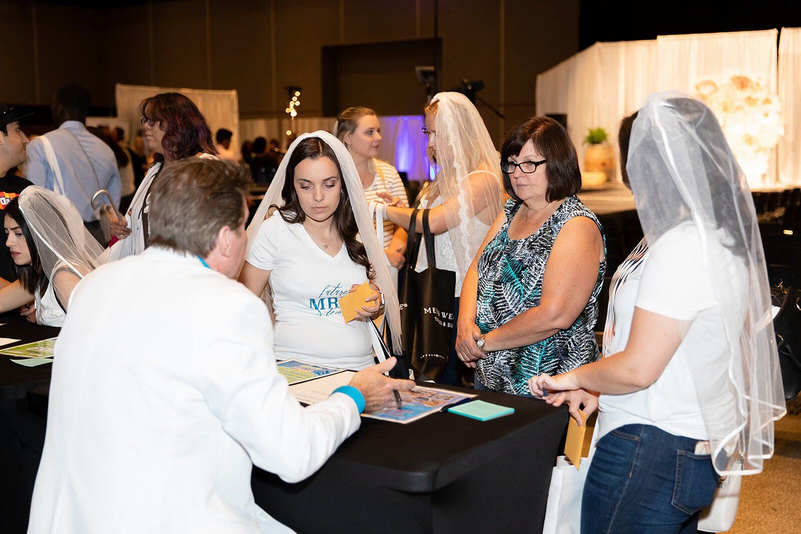 A group of women in veil are standing around a table.
