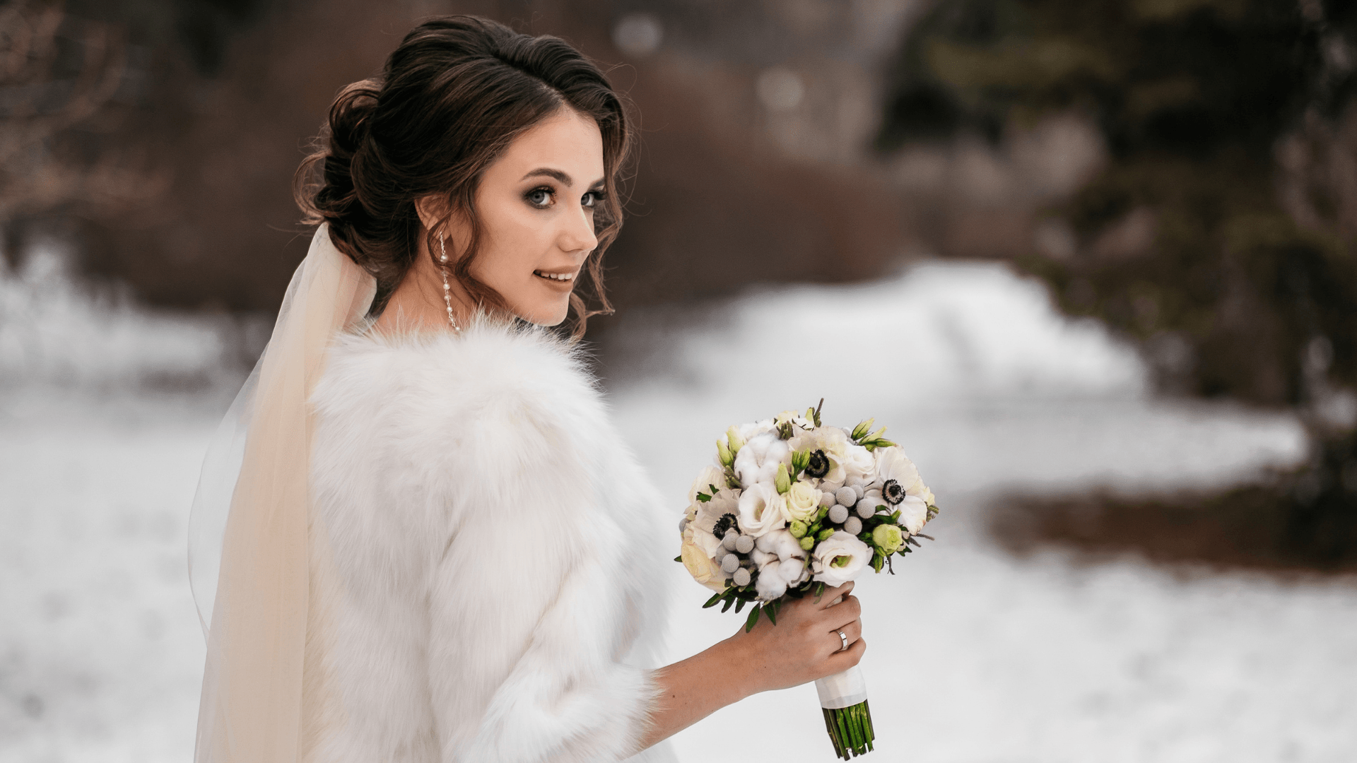 A bride in a fur coat is holding a bouquet of flowers in the snow.