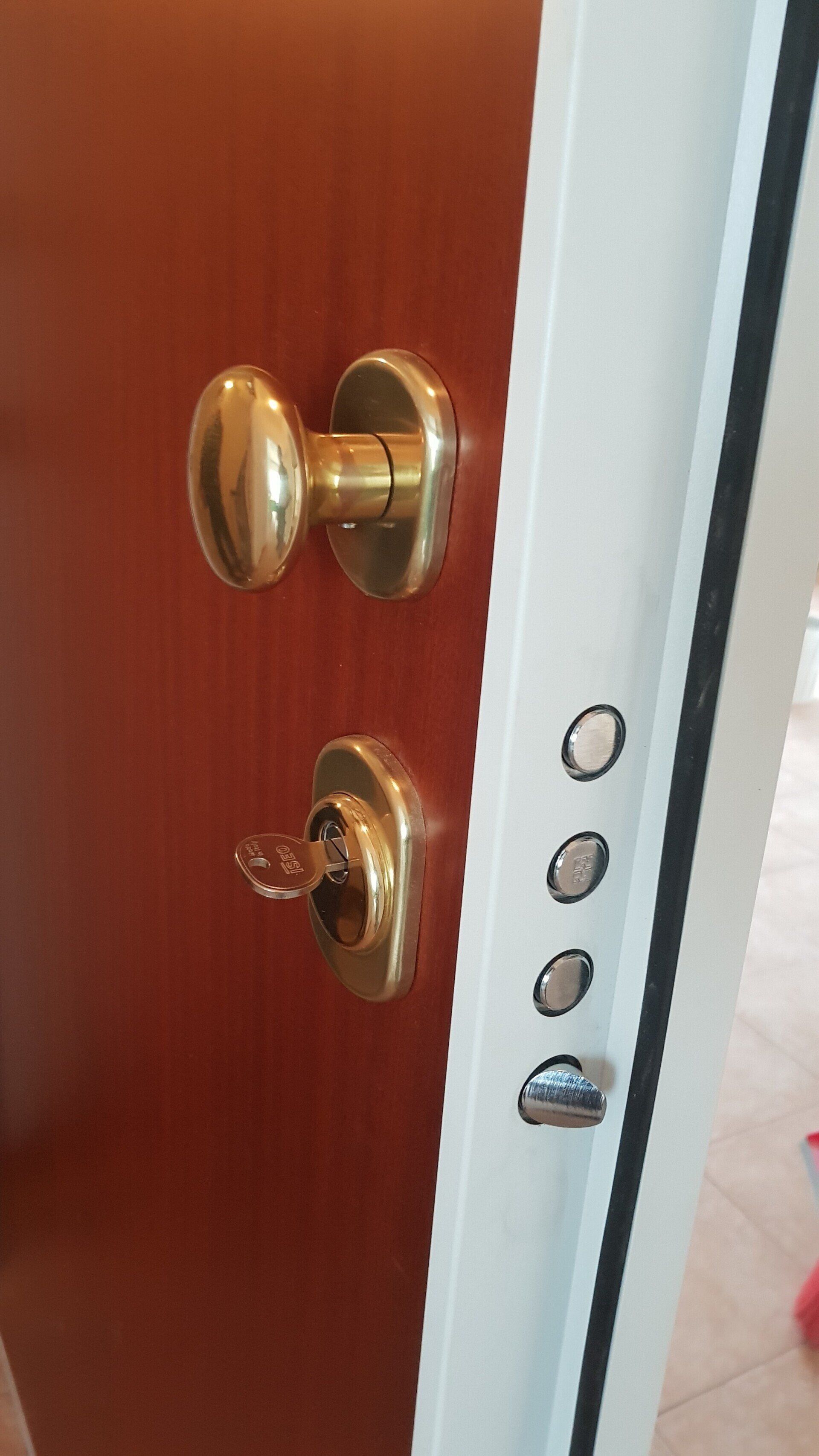 Primo piano di una porta marrone con pomelli in ottone e serratura a tastiera bianca sul telaio.