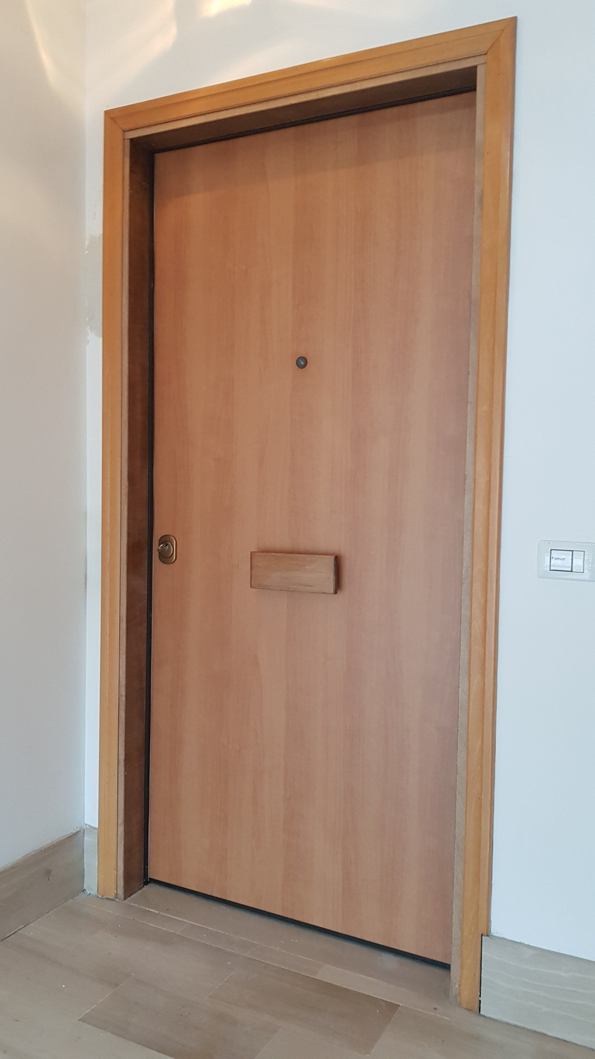Porta interna in legno con maniglia, incastonata in una parete e un telaio di colore chiaro.