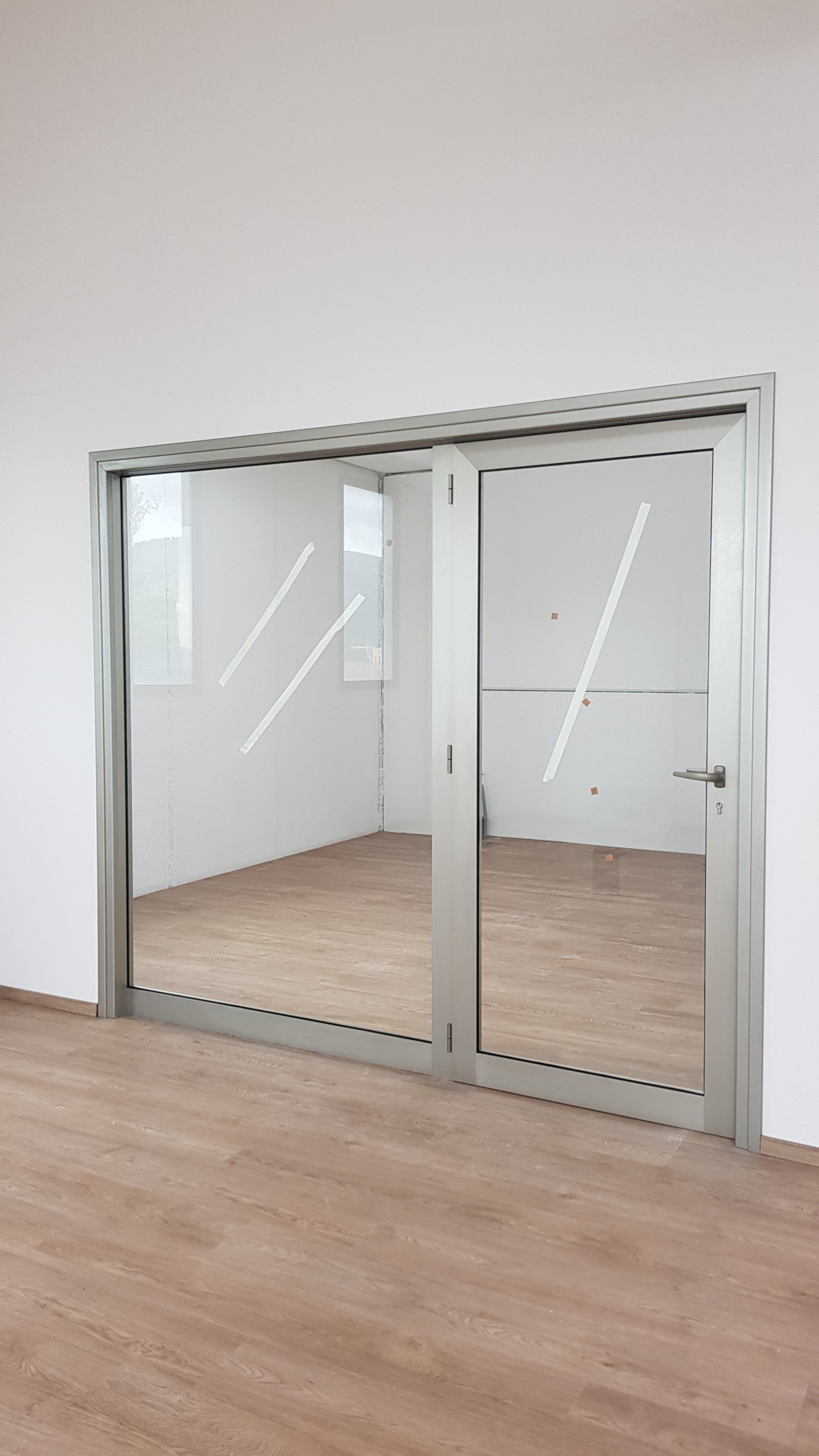 Stanza moderna vuota con porte scorrevoli in vetro e pavimento in legno chiaro.