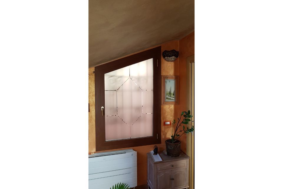 Ingresso in legno con porta in vetro satinato, elettrodomestico bianco, piccolo armadietto e pianta in vaso.