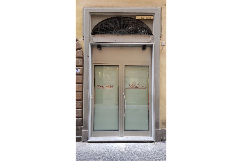 Porta d'ingresso chiusa in vetro con pannelli satinati e sopraluce ad arco su facciata in pietra.