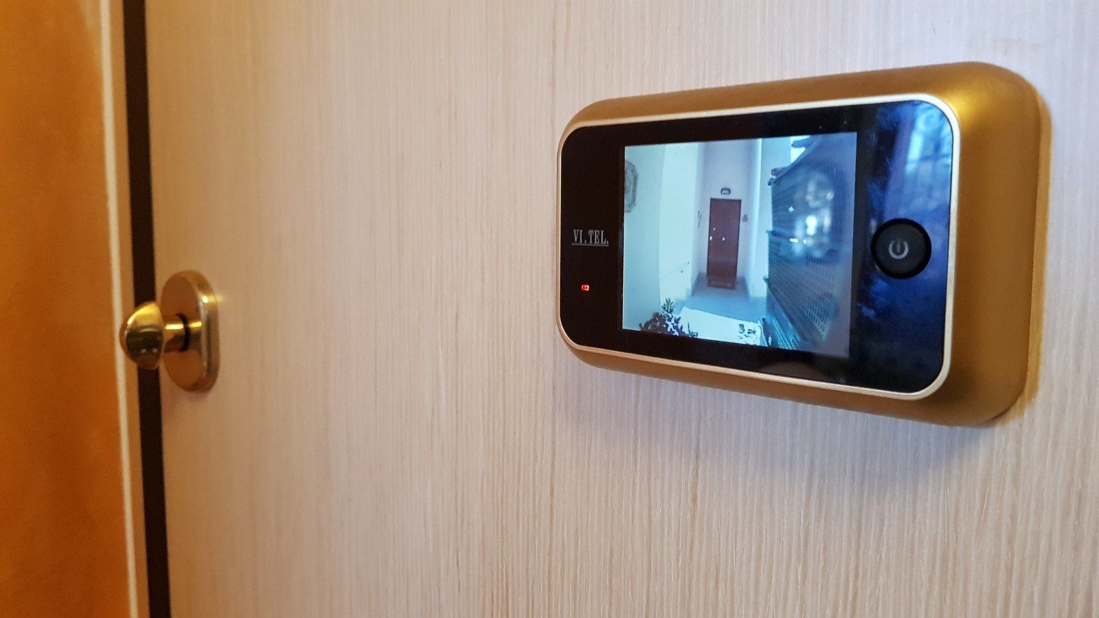 Spioncino digitale montato sulla porta di legno che mostra la vista del corridoio.
