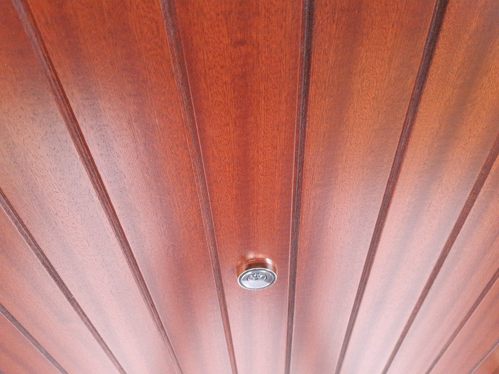 Soffitto rivestito in legno con una piccola lampada a incasso al centro.