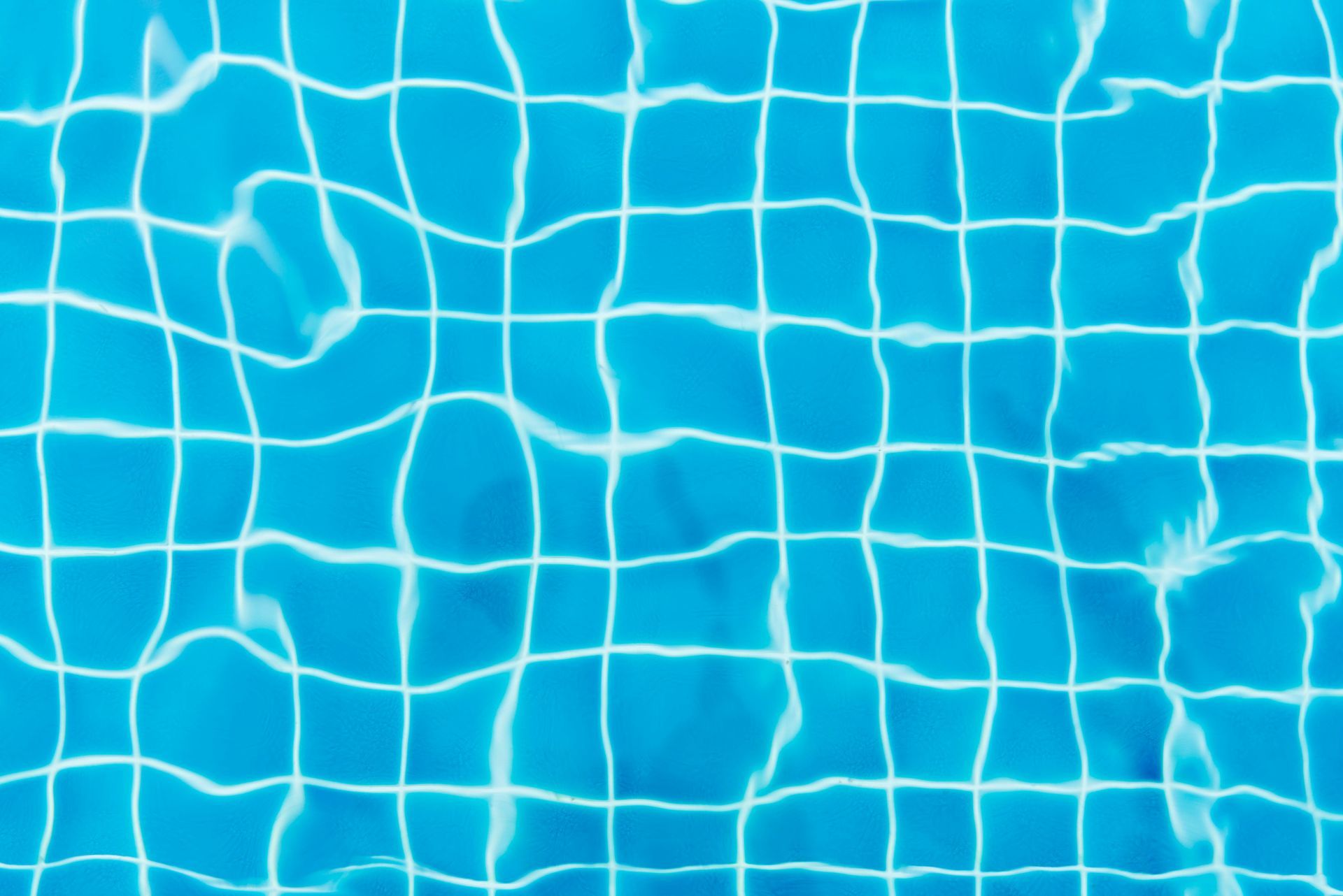 Blue swimming pool with a grid pattern of white lines, water surface rippling.