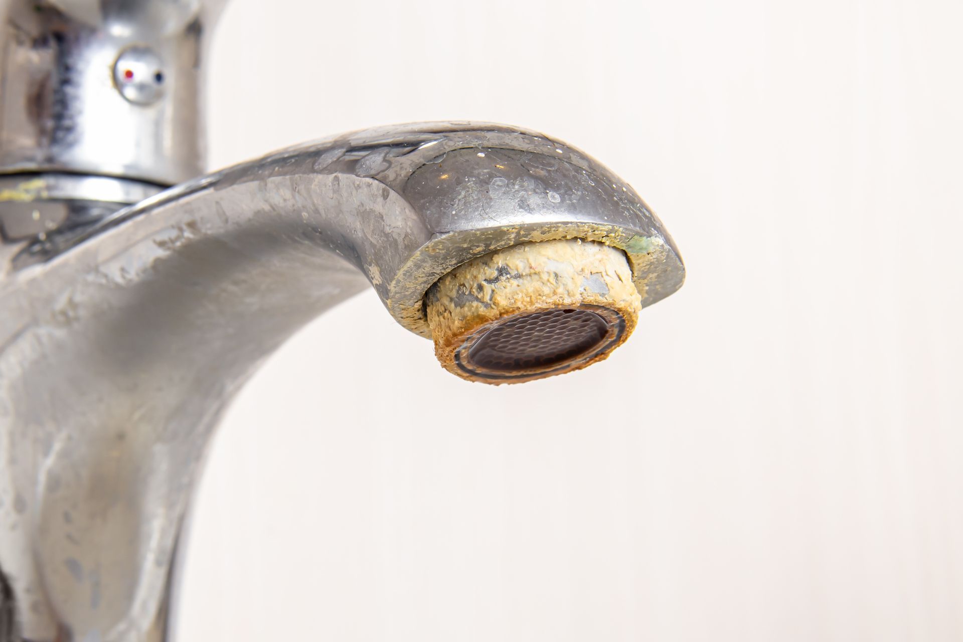 Close-up of a faucet with a clogged, rusty aerator.
