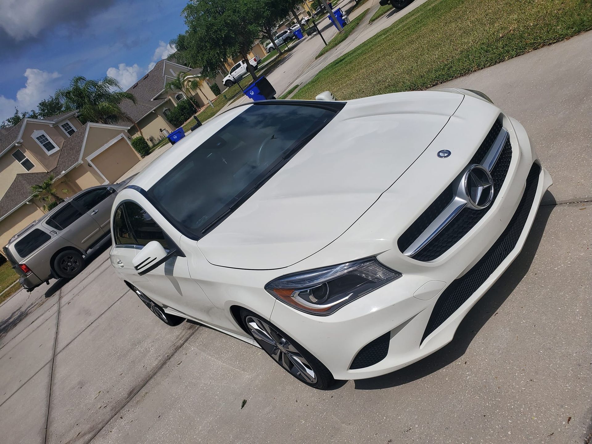 A white mercedes benz is parked on the side of the road