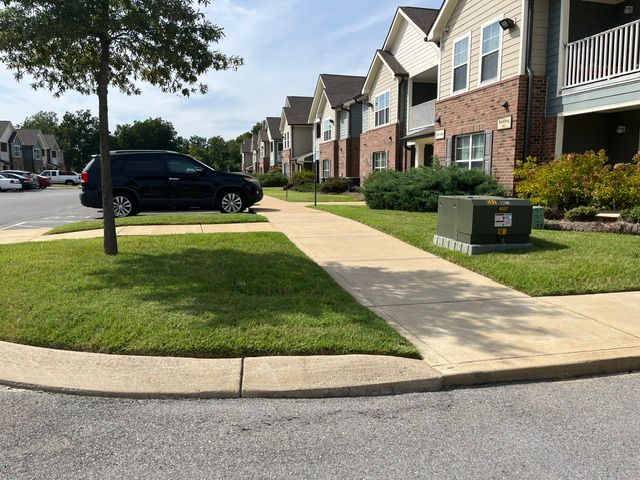 A black suv is parked on the side of the road in front of a row of houses.
