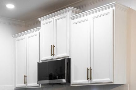 Person brushing dark wood stain onto a wooden cabinet in a bright workshop