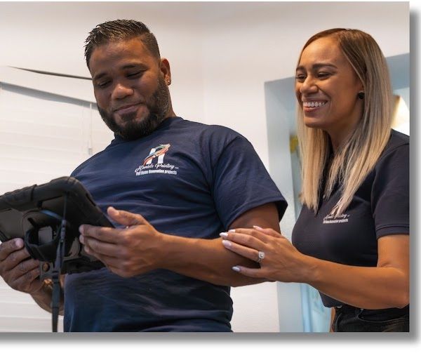 Two people in navy shirts smiling while looking at a handheld device indoors
