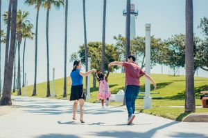 People walking and dancing on a sunny palm-lined park path