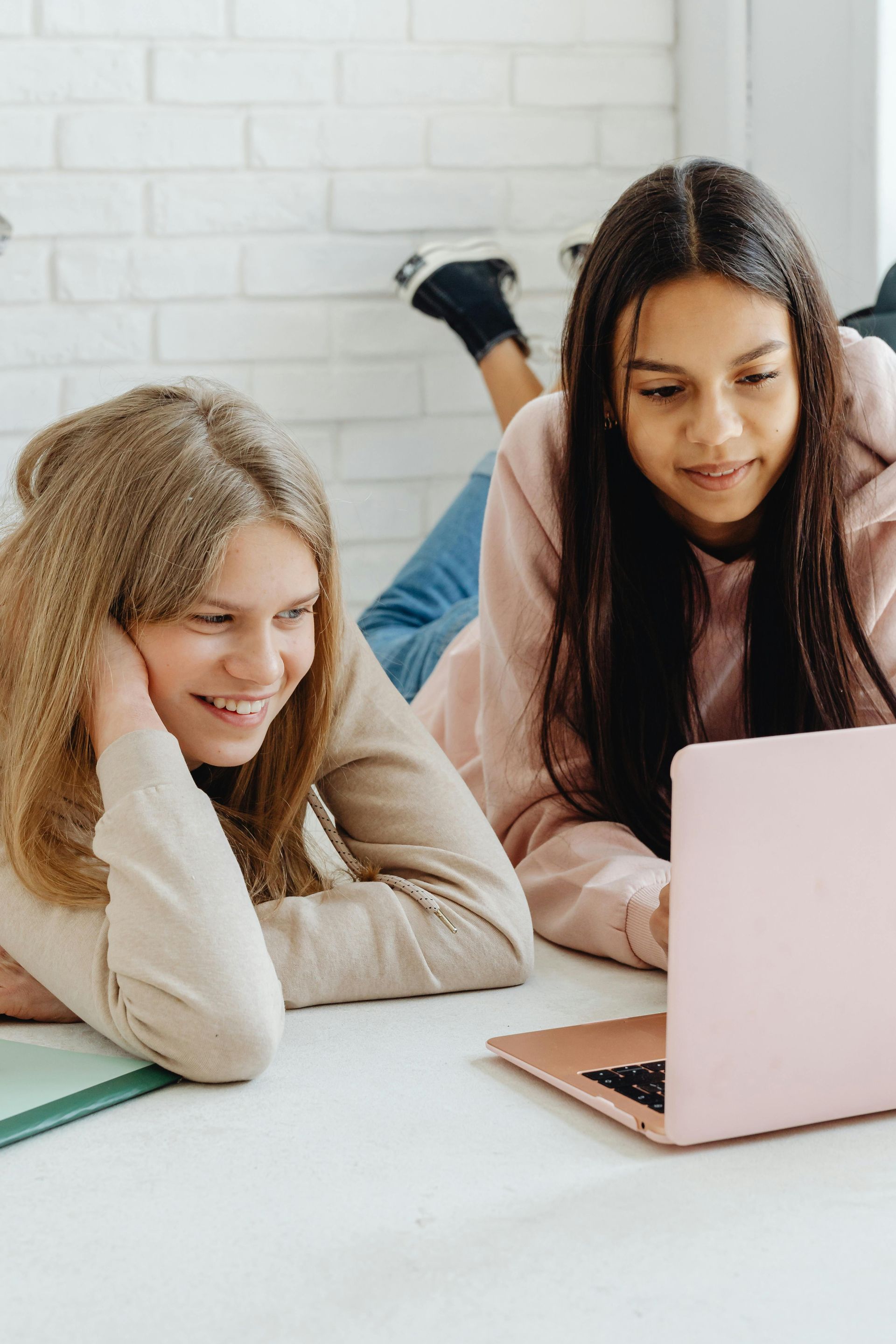 Two people smiling and looking at a laptop in a bright room