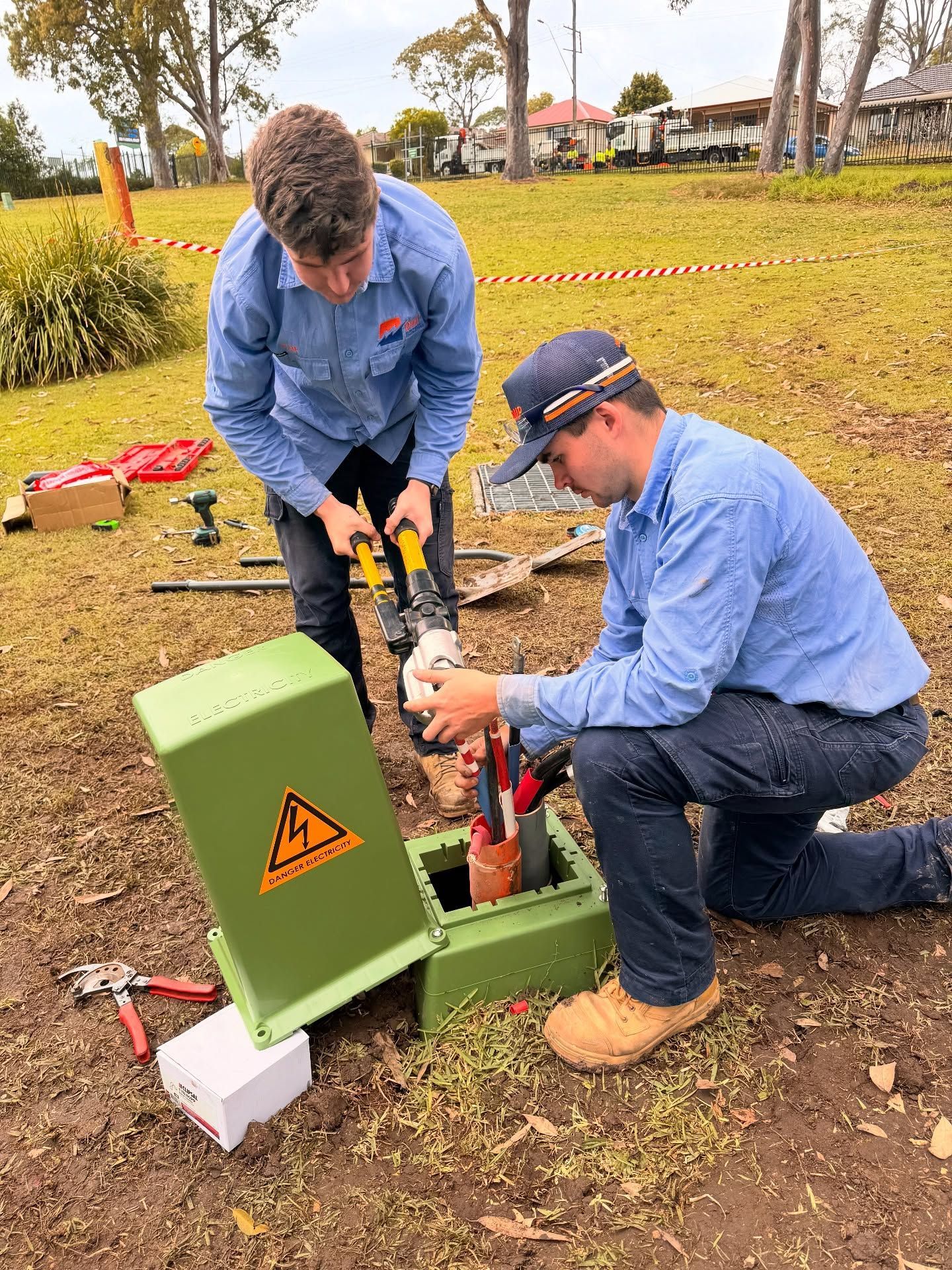 Two Workers in Blue Uniforms Installing Equipment — DMP Electrical Contractors In Nelson Bay, NSW